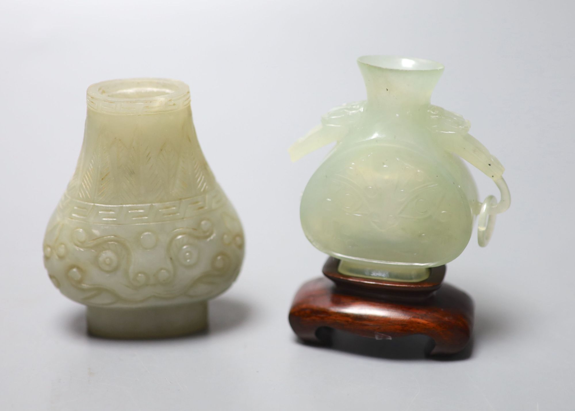 A Chinese celadon green jade vase, 7.4cm (lacking handles) and a Chinese bowenite jade vase, wood stand